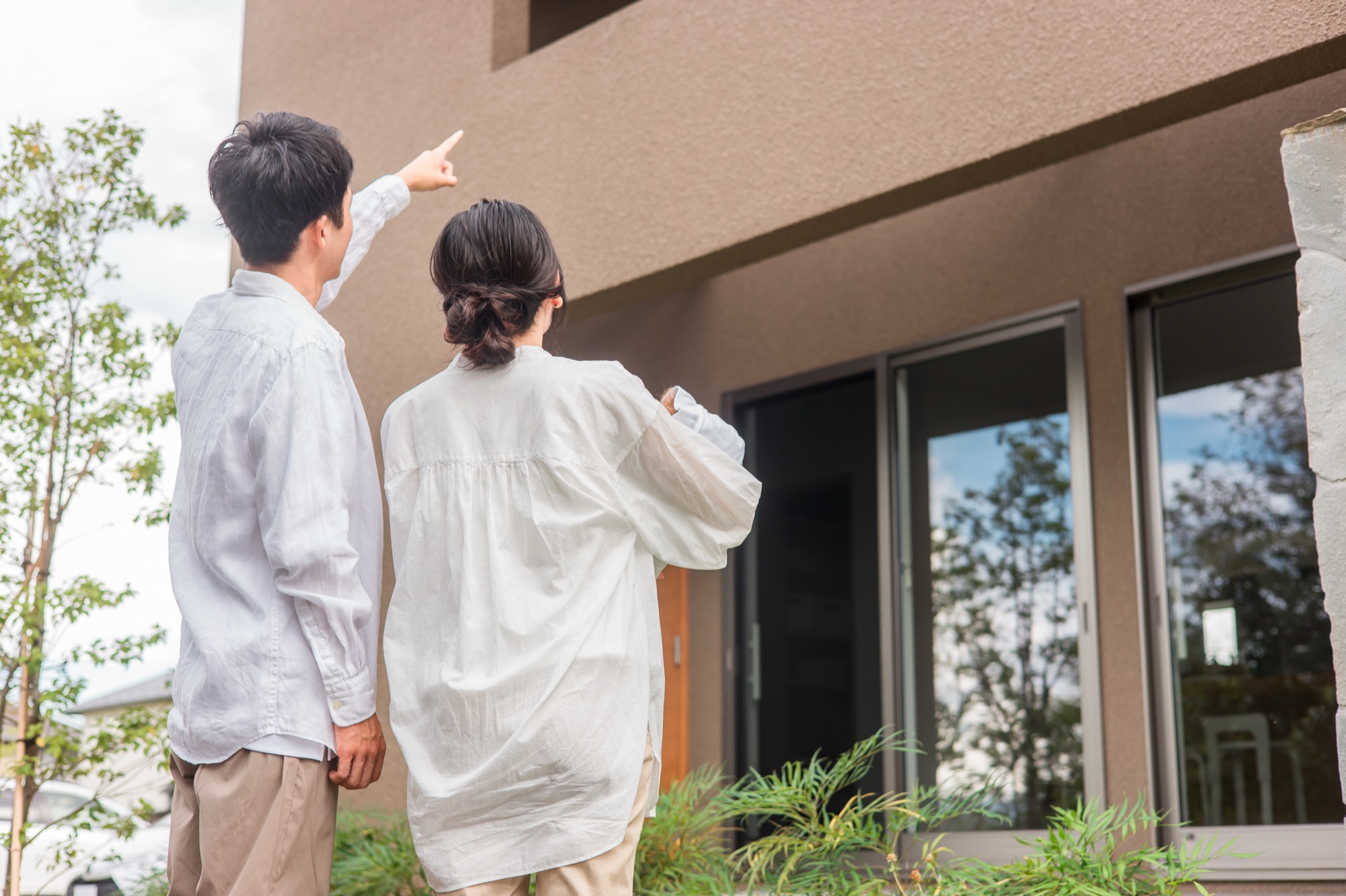 マイホームを指差す夫婦・家族（不動産・注文住宅・新築）